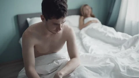 Unhappy couple having problem in bedroom. Frustrated man sitting on bed apart Stock Footage 141820595