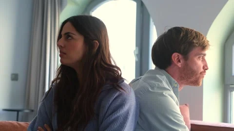 Unhappy Couple Sits Back-to-Back After an Argument, Showing Relationship Conflic Stock Footage 332684283