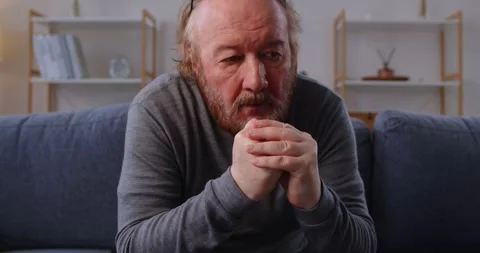 Unhappy elderly man sitting alone on sofa, feeling grief, loneliness and painful Vídeo Stock 314032451