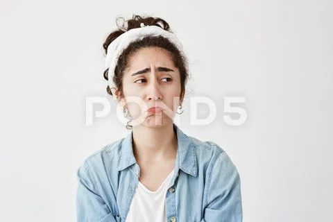 Unhappy female with dark and wavy hair pouting lips, being sad after quarrel Stock Photos