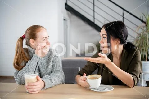 Unhappy female friends discuss shocking news. Two shocked young women covering Stock Photos