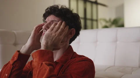 Unhappy man in his 30s thinking about life problems while sitting on the floor Stock Footage 337908294