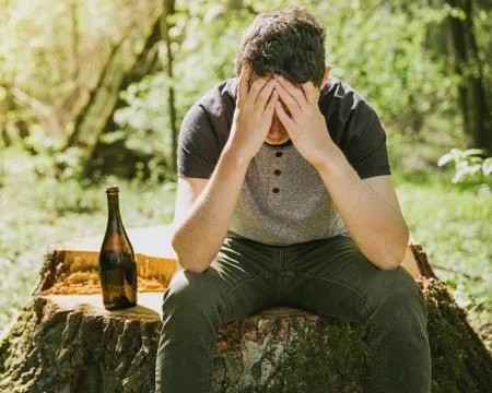 An unhappy man solves problems with alcohol. sad and alone with a bottle of Stock Photos
