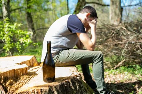 An unhappy man solves problems with alcohol. sad and alone with a bottle of Stock-Fotos