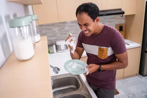 Unhappy man while washing dishware Stock Photos