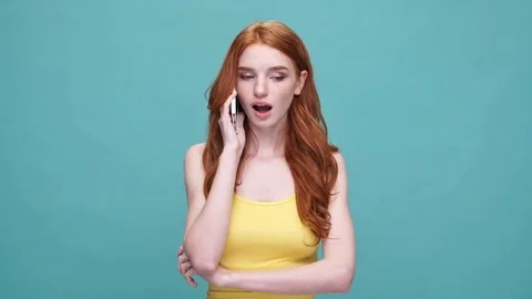 Unhappy redhead lady talking on smartphone isolated Stock Footage