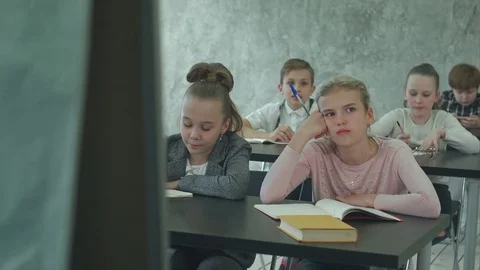 Unhappy schoolgirl in class listen to a teacher Stock Footage
