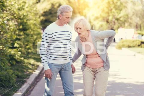 Unhappy senior woman feeling pain in the back Stock Photos