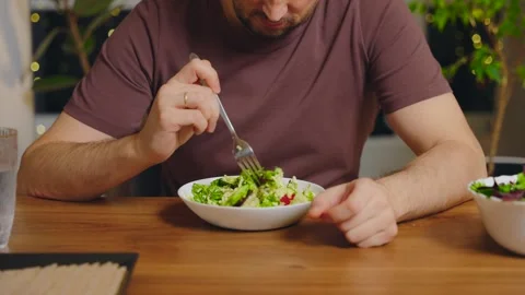 Unhappy thoughtful man picking at his plate sitting at table healthy vegetable Stock Footage 323929514