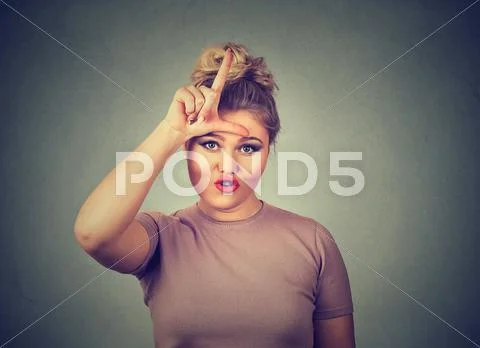 Unhappy woman giving loser sign on forehead, looking at you, disgust on face Stock Photos