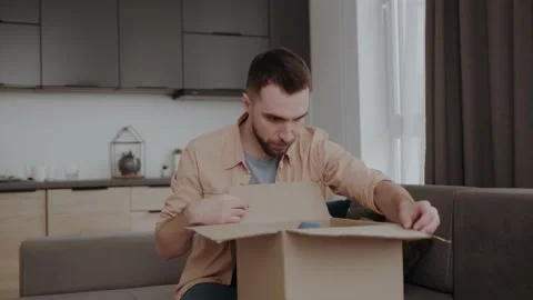 Unhappy young man looking inside delivery parcel, dissatisfied with damaged item Stock Footage 156404458