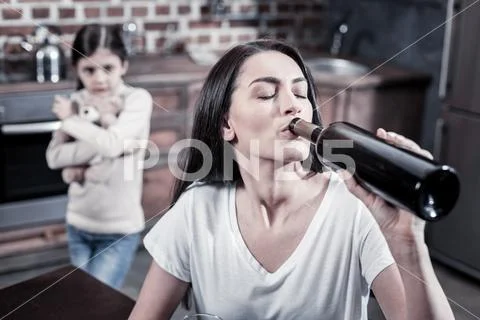 Unhappy young woman drinking alcohol Stock Photos