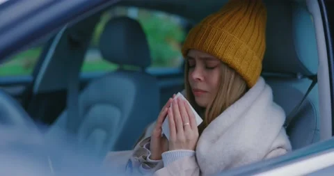 Unhealthy girl young sick woman sitting in car suffering fever allergy sneezing Stock Footage 143737280