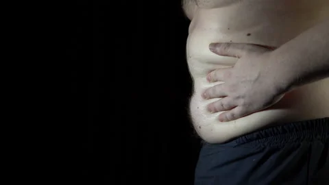 Unhealthy man checking his belly in front of dark background. Stock Footage 86107532