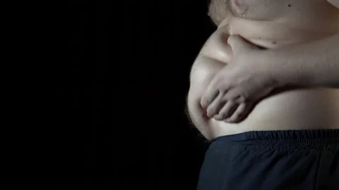Unhealthy man checking his belly in front of dark background. Stock Footage 86108550