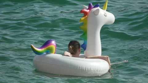 Unicorn Float Ocean Summer: A person enjoys the water on a white inflatable Stock Footage 283810811