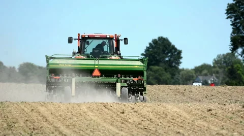 An unidentified farmer on a tractor spreads soybeans on a farm Stock Footage