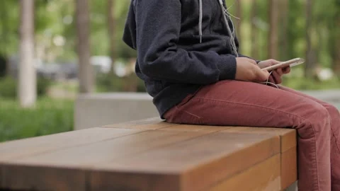 Unidentified kid sitting and using smartphone outdoors Video stock 132999264