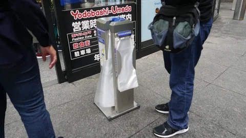 Unidentified man demonstrates how to use automated machine to wrap wet umbrella Stock Footage 98586015