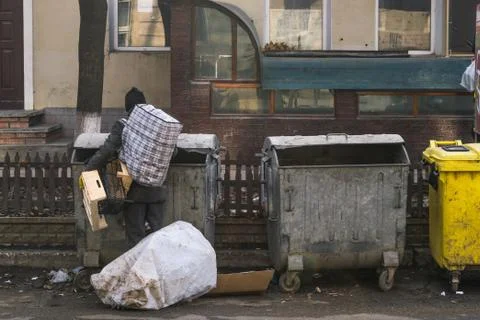 An unidentified man looking for something in the garbage can Stock Photos