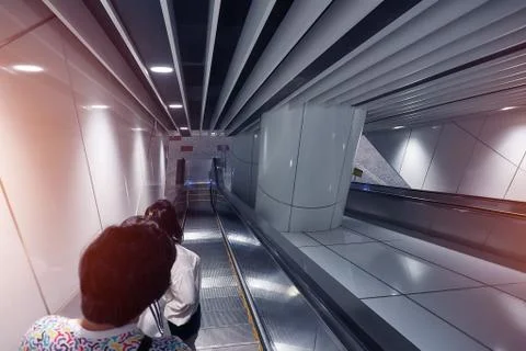 Unidentified people using automatic ladder escalator going dowstair Stock Photos