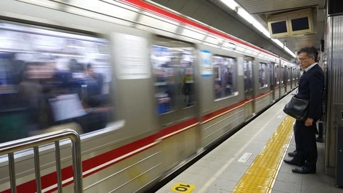 Unidentified people wait for train to stop in Osaka, Japan. Видео 98578005