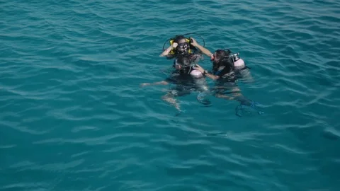 Unidentified scuba divers before diving. The instructor helps the student to Stock Footage 91265029