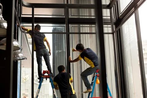 Unidentified worker applying tinted layer on glass window Stock Photos