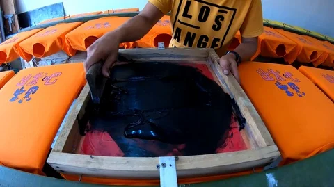 Unidentified worker man using Silk screen printing on clothing fabric technique Stock Footage 104444721