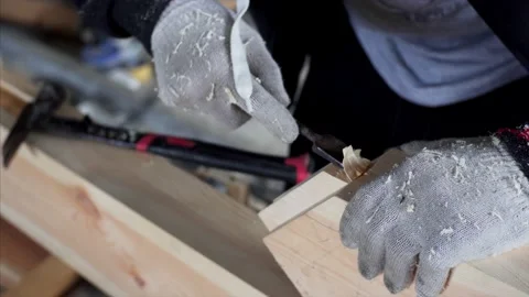 An unidintified carpenter in gloves is working with chisel in his workshop Stock Footage 142000376