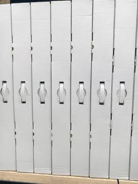 Uniform handled boxes in white cardboard arranged on electronics store shel.. Photos
