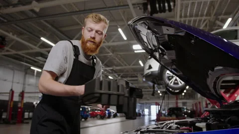 Uniform mechanic disassembles the car to replace the filter Stock Footage 253390386