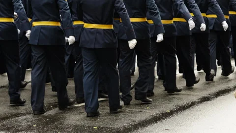 Uniformed marching unit in blue dress attire with yellow belts advances in tight Stock Footage 335263258