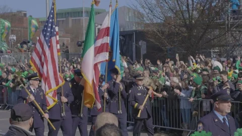 Uniformed officers march with flags during Dublin's St. Patrick's Day parade Video stock 334686175