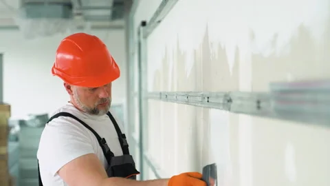 A uniformed worker applies plaster to the drywall wall. Putty of joints of Vídeos de archivo 245550820