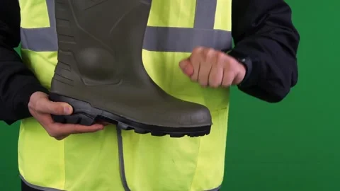 A uniformed worker checks the strength of a boot on a green background Stock Footage 162035501