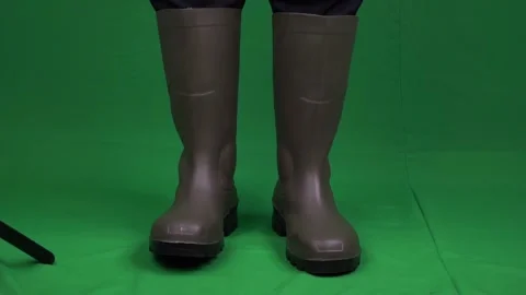 A uniformed worker shows rubber boots on a green background Stock Footage 162035528