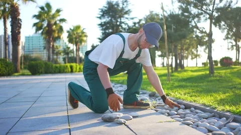 Uniformed worker using decorative cobblestones in the garden or in the park wide Video stock 238898798