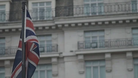 Union Flag / Union Jack Flag in gentle breeze with flats with balconies behind Stock Footage 93329010