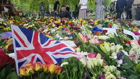 UNION JACK FLAG AND FLOWERS LEFT AS MOURNERS GRIEVE LOSS OF QUEEN LONDON 2022 Stock Footage 210893684
