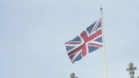 Union Jack flag blowing in slow motion against blue sky Stock Footage 86649733