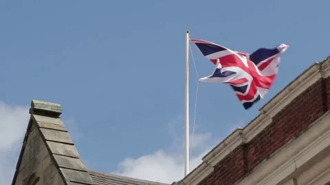 A Union Jack flag flutters against a clear blue sky Stock-Footage 73497024