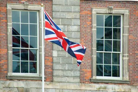Union Jack Flag Flutters Between Georgian Windows on Historic Building Stock Photos