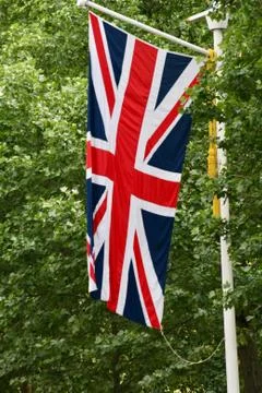 Union Jack flag flying vertically with trees in the background Stock Photos