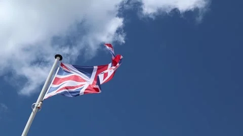 Union Jack flag waving in the wind against a clear blue sky Stock Footage 312253870