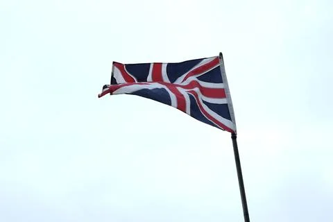 Union Jack flag waving in the wind against a blue sky. Stock Photos