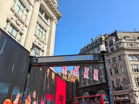 Union Jack flags flying over iconic Oxford Circus buildings under a clear blue Stock Photos