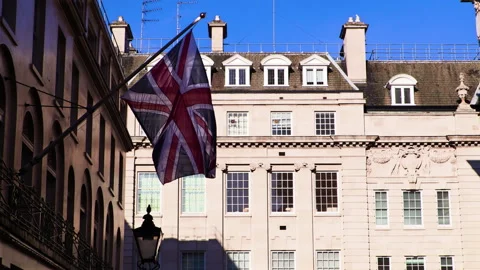 Union Jack fluttering in the wind on a sunny London street Stock Footage 142739760