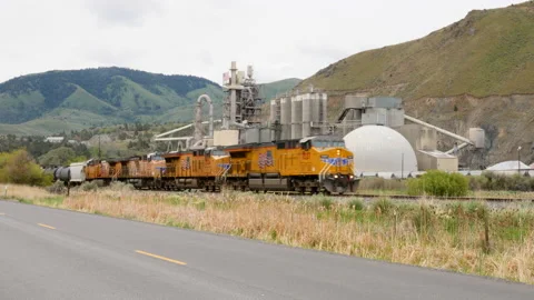 Union Pacific freight train passes Ash Grove Cement, Baker City, Oregon. Stock Footage 132118078