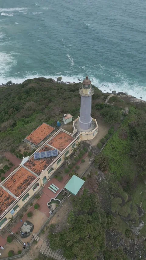 Unique aerial view of lighthouse and surrounding greenery in coastal area Video stock 310851440
